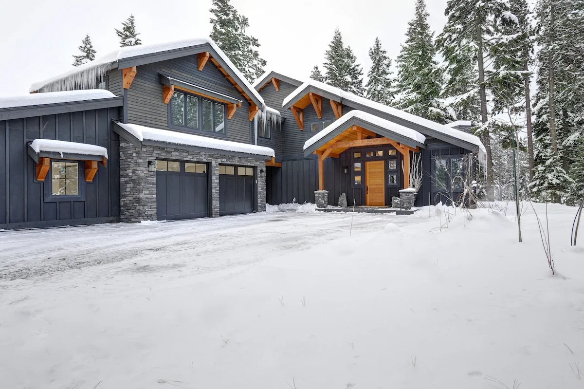 Modern mountain custom home with stone, dark siding, and timber accents built by Aloe Contracting
